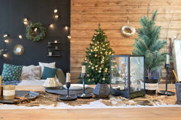 On the eve of the holiday, the interior of the country house is decorated with a New Year tree. large spacious light room decorated with wood with simple wood furniture