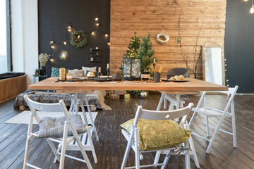 On the eve of the holiday, the interior of the country house is decorated with a New Year tree. large spacious light room decorated with wood with simple wood furniture