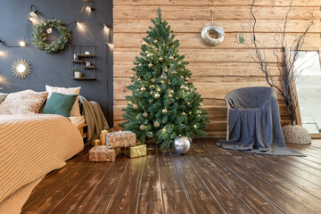 On the eve of the holiday, the interior of the country house is decorated with a New Year tree. large spacious light room decorated with wood with simple wood furniture
