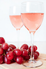 Glasses of rose wine and red grapes on white background. two glasses of champagne