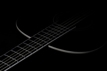 Obraz na płótnie Canvas low-key photo of a fragment of a black guitar against a dark background. guitar music photo aesthetic