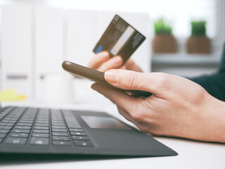 young woman holding credit card and using laptop and smartphone. Online shopping, booking and banking concept. Businesswoman or entrepreneur in the home office.