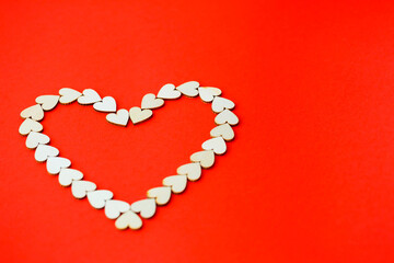 Heart lined with wooden hearts on a bright red background. Place for an inscription, romantic picture for Valentine's Day