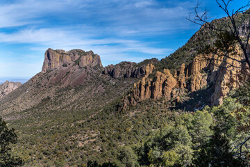 A flat top craggy mountain a part of a larger ridge with colorful rocky cliffs and trees on the slops, Casa Grande Peak, Big Bend National Park, Texas