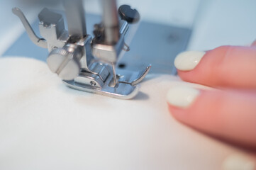 Close-up. A woman works on an electric sewing machine at home