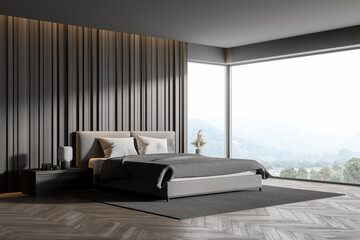 Corner of master bedroom with grey wooden walls, panoramic window with countryside view,...