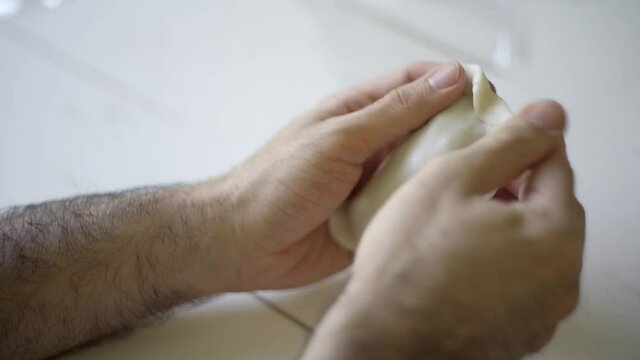 Close up of male hands preparing an argentinean empanada over a white table. Putting the filling and closing it with a home made traditional repulgue.