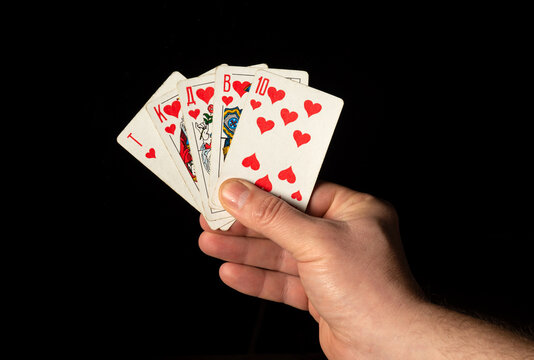 Close up male hand holding Royal Flush cards while playing poker