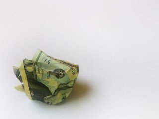 Crumpled bill, with a spherical shape, lying on the ground.