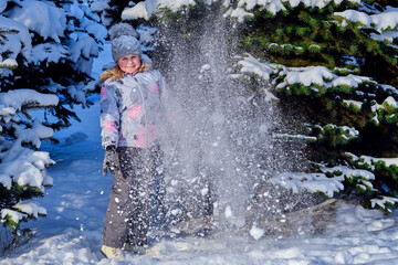 The girl plays with snow. Child rejoices in winter. Happy childhood.