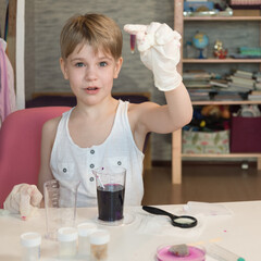 A child chemist admires the results of a scientific experiment. A child biologist studies small...