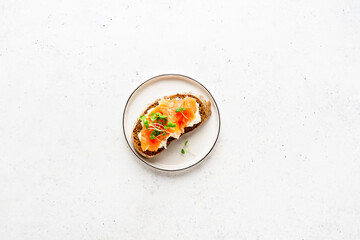 Toasted bread with ricotta (cream cheese), smoked salmon and micro greens on plate. Health care, super food concept. White Stone background. Top view. Copy space.