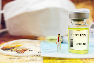 Miniature people : Doctor stand on medical mask with COVID-19 vaccine  and syringe. Vaccine and Healthcare Medical concept.