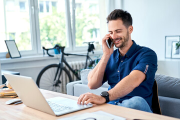 Young man talking on the phone working at home office