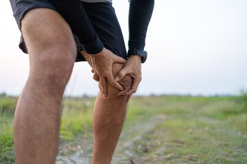 sporty man suffering with knee pain while exercising outdoors