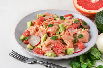 Chilean salmon ceviche with grapefruit, avocado, radish, onion and mint in a plate with fork. Healthy diet food