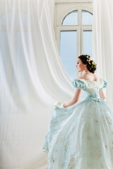 A beautiful elegant dark haired woman in a historic 1867 dress on background with window. High quality photo