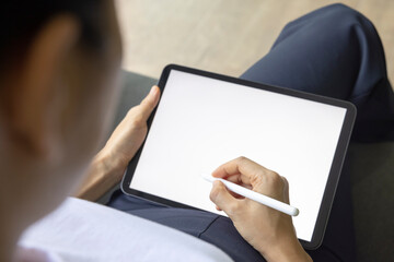 Close-up woman drawing of hand held with digital tablet white screen on sofa in the living room. Concept of technology, connection, communication