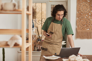 Waist up portrait of young artisan using laptop in crafting workshop, small business concept, copy space