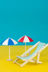 Beach relaxation and vacation concept. Toy sun lounger and umbrella on colorful paper background.

