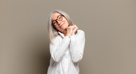 senior woman feeling in love and looking cute, adorable and happy, smiling romantically with hands...