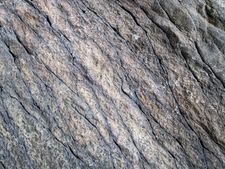 Layered texture of old stone. Shabby long-term stone. Ribbed texture with cracks and grains.