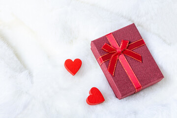 Red gift box and two hearts in furry white bed for Valentine day