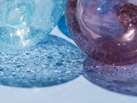 macro of transparent glass balls on light blue background with shadow, blue tones