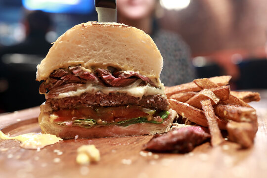 Half burger with fries on wooden board