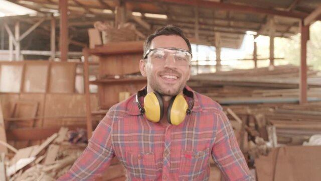 Portrait of happy Caucasian professional successful carpenter smiling and laughing then crossing arms at work place.