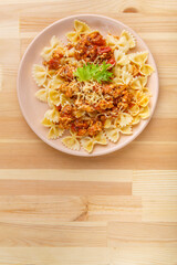 Pasta in tomato bolognese sauce in a plate on a wooden table. copy space