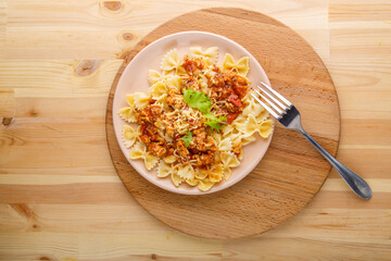 Pasta in tomato bolognese sauce in a plate on a wooden table on a round stand