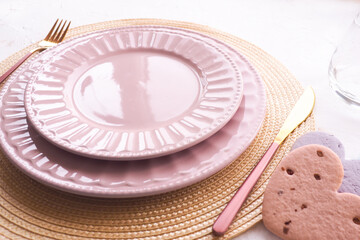 table setting. two empty pink plates, spoon and fork on a white table. copy space..