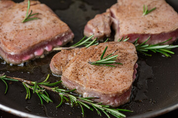 Tuna steaks cooking in frying pan with rosemary. Healthy diet food