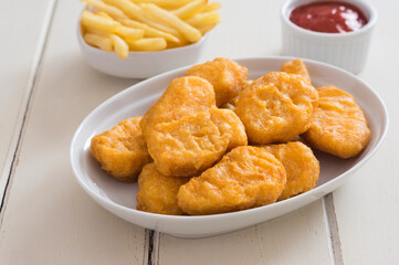 Chicken nuggets with potatoes chips and ketchup sauce.