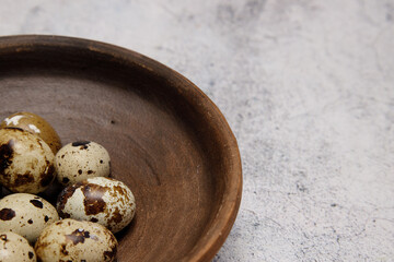 fresh quail eggs from the farm in a plate of brown clay on a gray marble table. selective soft focus. High quality photo