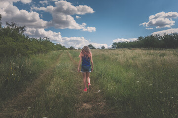 Naklejka premium child in green nature walking along back view