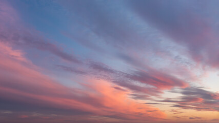 Dramatic vanilla skyscape. Purple orange sunset clouds against blue sky. Scenic dynamic low clouds...