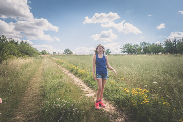 Fototapeta na wymiar happy smiling child walking in green meadow in scenic sunny day