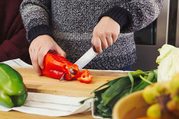 Stock photo of a close up shot of a man's hands cutting vegetables in the kitchen, preparing a vegan food and healthy meal