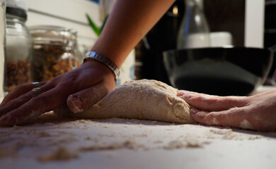 Fototapeta premium hands of a young woman with a bread dough in a white table