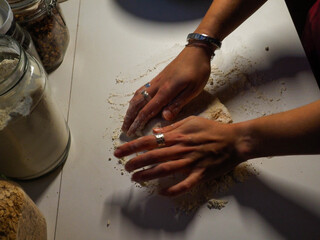 hands of a young woman with a bread dough in a white table