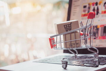 Shopping online. cardboard box with a shopping cart logo in a trolley on laptop keyboard. Shopping...