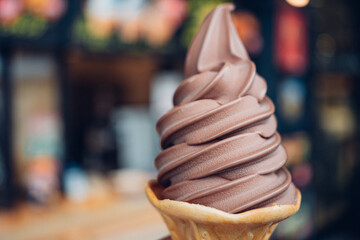 The soft chocolate ice cream with the wafer cone on blured bacground