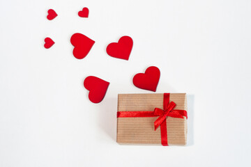 a gift with a red ribbon with hearts on a light background. Top view