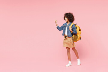 Fototapeta na wymiar Full length happy little african american kid school girl 12-13 year old in casual clothes, backpack do winner gesture clench fist look aside isolated on pink background. Childhood education concept