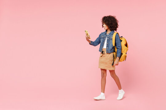 Full length happy smart smiling little african american kid school girl 12-13 year old in casual denim clothes backpack hold hands back of head isolated on pink background Childhood education concept