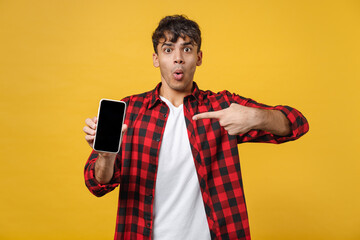 Young spanish latinos surprised man in red checkered shirt hold point index finger on mobile cell...