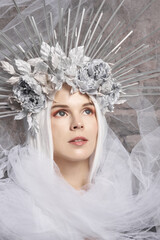 Portrait of winter queen. Attractive young woman in dress, veil, silver flower crown