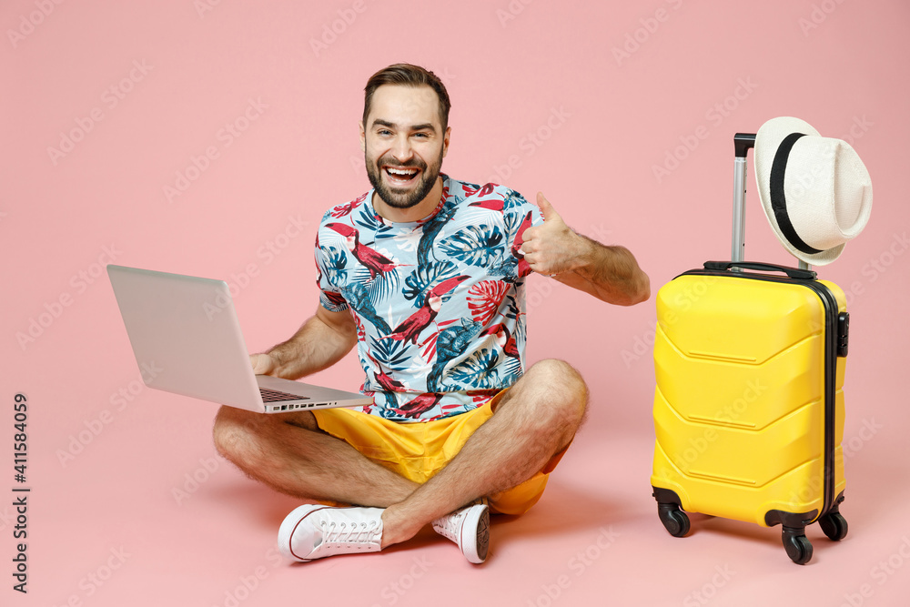 Wall mural full length of cheerful traveler tourist man sit on floor work on laptop computer booking hotel show